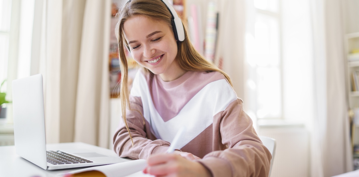 Young female student sitting at the table, using laptop when studying.